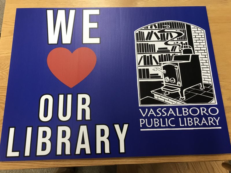 A yard sign with the VPL logo that says "We Love Our Library"